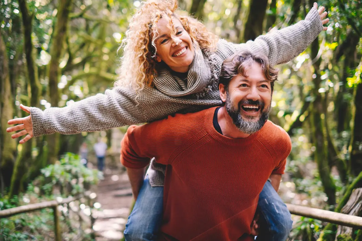 Overjoyed mature couple walking through park
